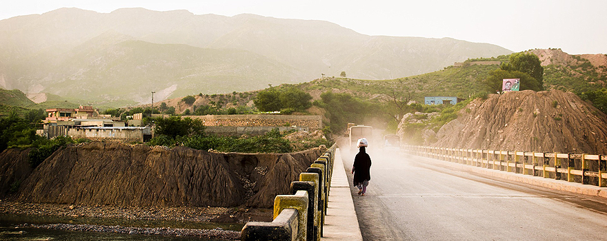 A woman crosses a bridge in a rural area of Pakistan [Pixabay].